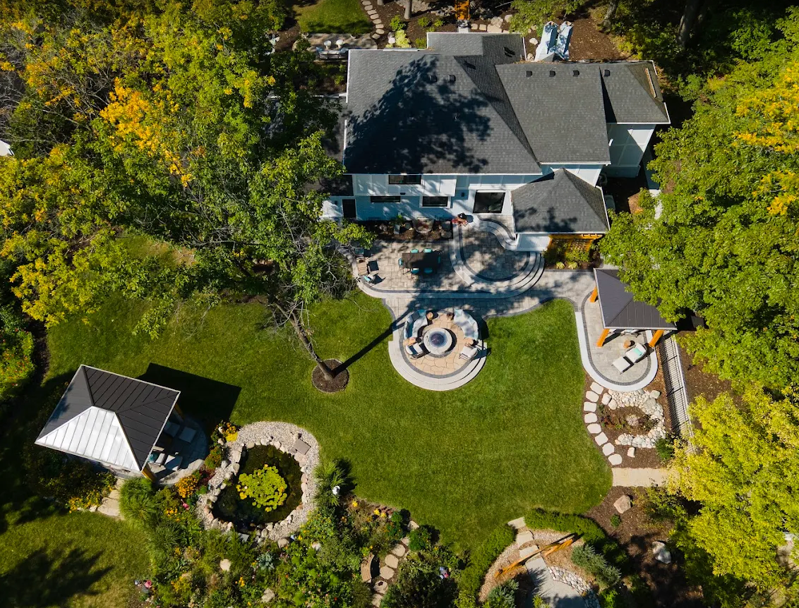 Aerial view of a beautifully landscaped Oakville backyard with patio, fire pit, lawn, and garden beds